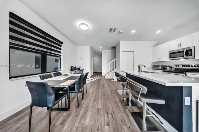 a open kitchen with a table chairs a sink dishwasher stove and microwave oven with wooden floor