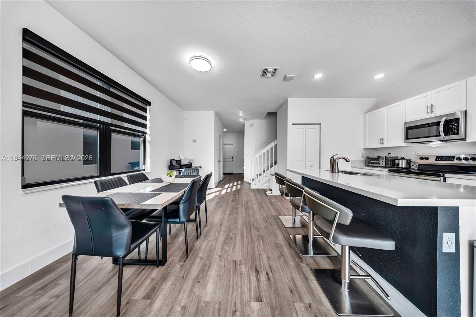 24985 Southwest 107th Court Homestead, FL 33032 - Photo 9 of 22 a open kitchen with a table chairs a sink dishwasher stove and microwave oven with wooden floor
