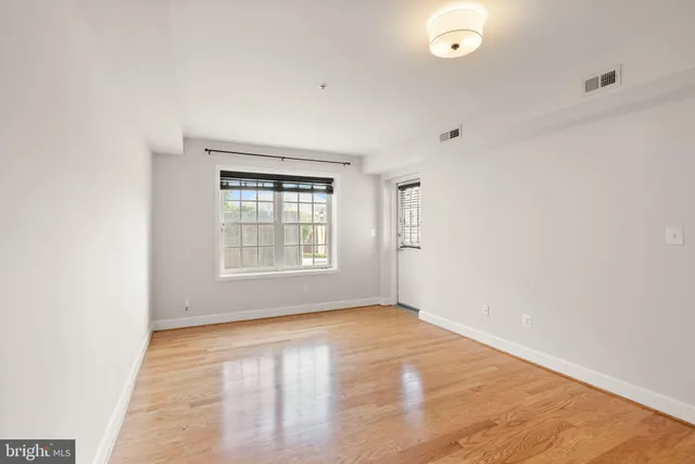 an empty room with wooden floor and windows