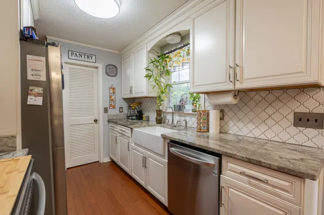 a kitchen with stainless steel appliances granite countertop a sink a stove and a refrigerator