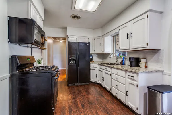 a kitchen with granite countertop a refrigerator stove and sink