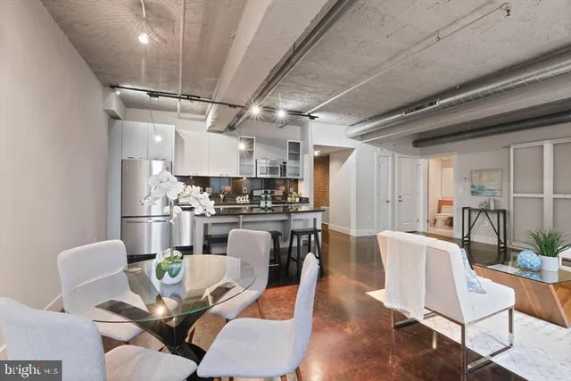 a kitchen with stainless steel appliances kitchen island granite countertop a dining table chairs refrigerator and sink