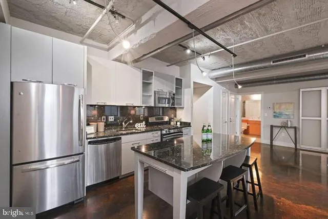 a kitchen with stainless steel appliances a dining table chairs refrigerator and stove