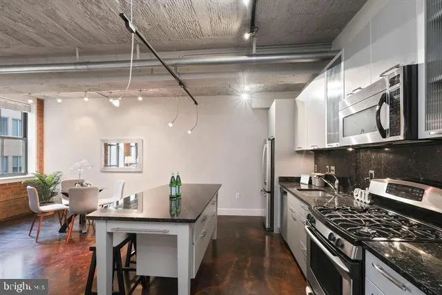 a kitchen with stainless steel appliances granite countertop a stove top oven a dining table and chairs with wooden floor