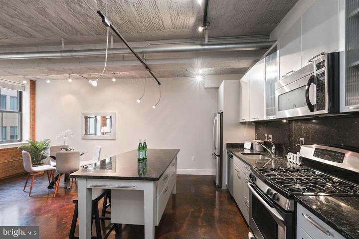 916 G St. Northwest, Unit 602 Washington, DC 20001 - Photo 6 of 11 a kitchen with stainless steel appliances granite countertop a stove top oven a dining table and chairs with wooden floor