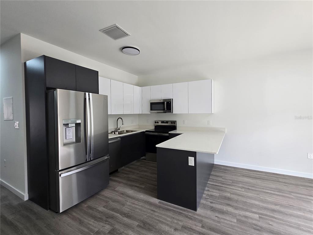 1601 Northwest 29 Road, Unit 3 Gainesville, FL 32605 - Photo 16 of 48 a kitchen with stainless steel appliances a refrigerator a stove a sink and white cabinets with wooden floor
