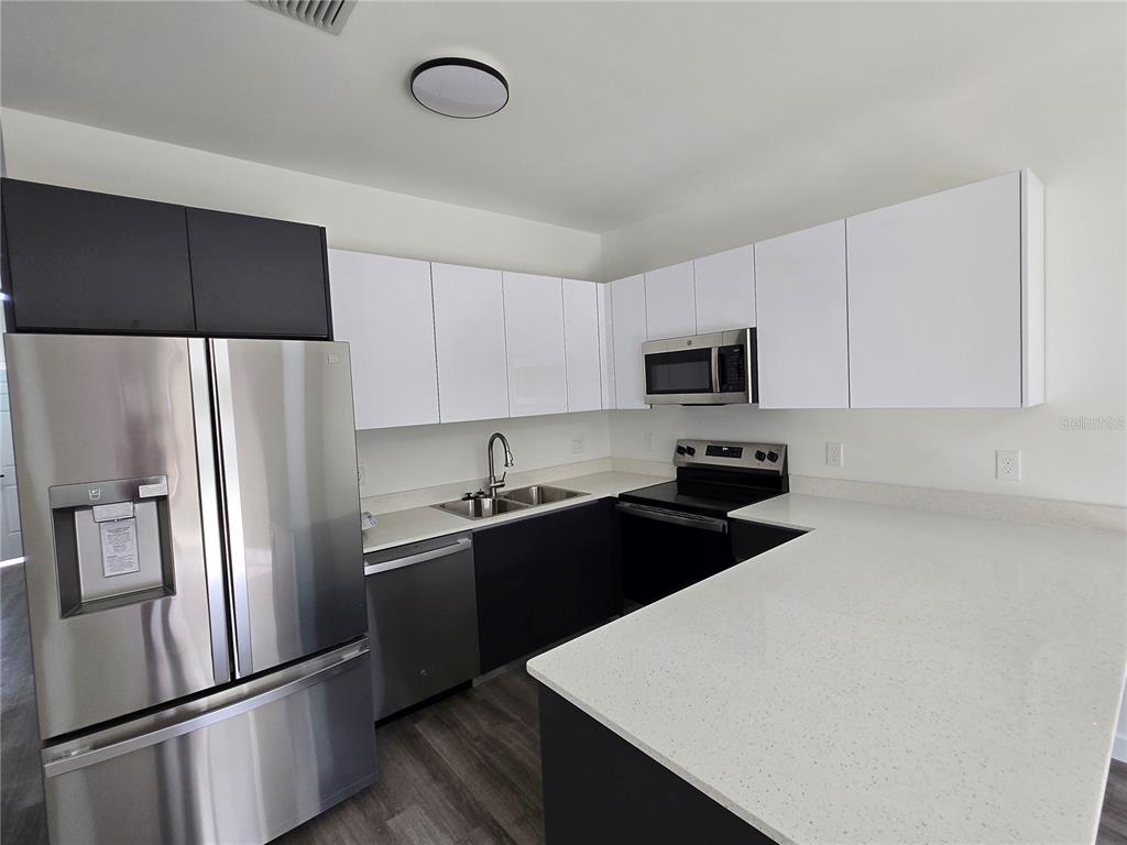 1601 Northwest 29 Road, Unit 3 Gainesville, FL 32605 - Photo 17 of 48 a kitchen with a refrigerator a microwave a sink and cabinets