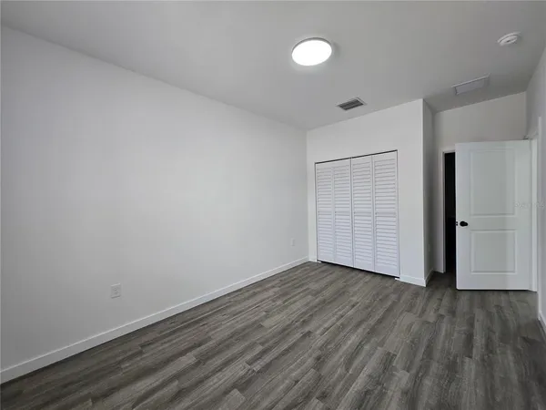 a view of an empty room with wooden floor and closet