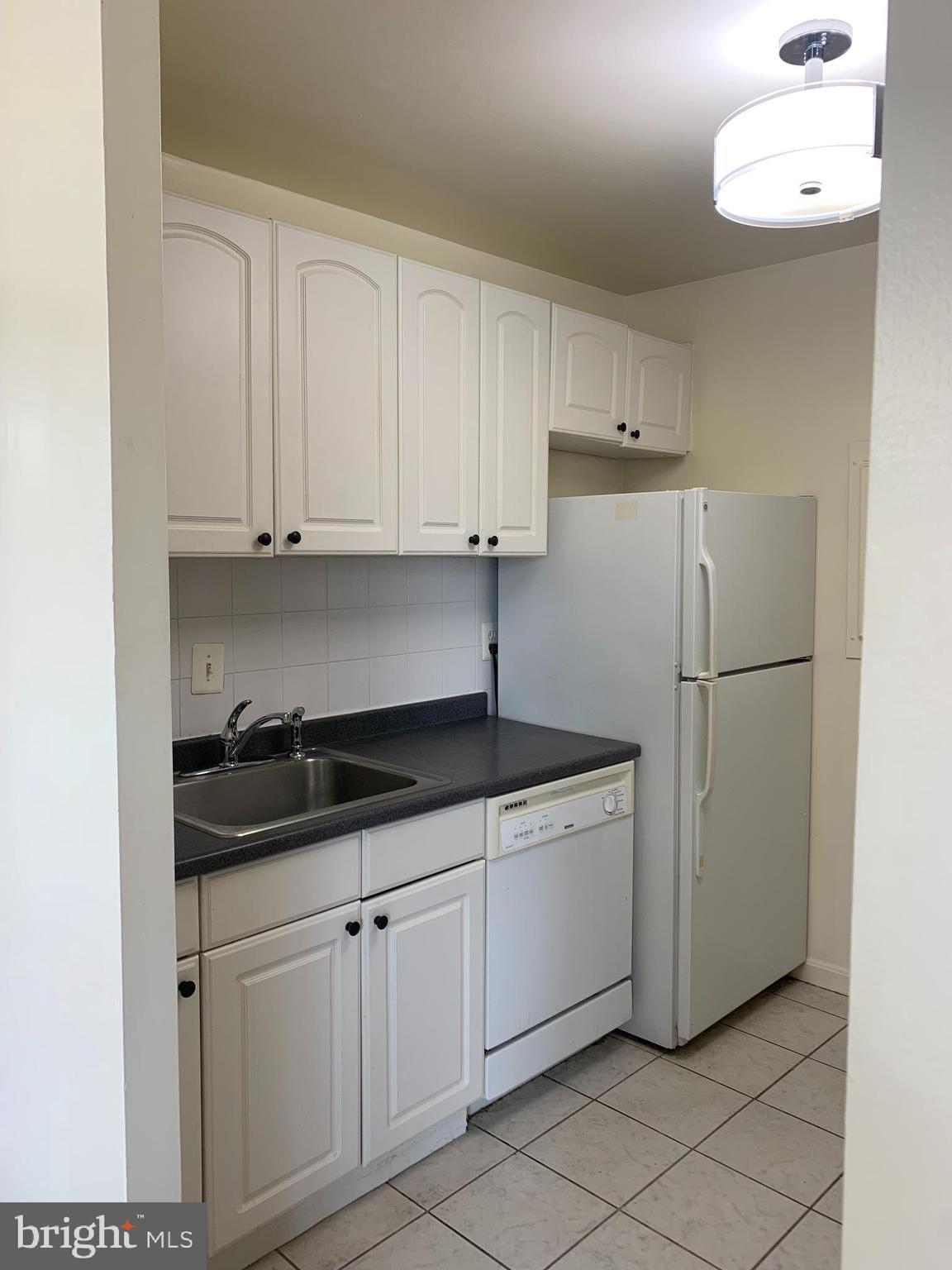 3245 Rio Drive, Unit 307 Falls Church, VA 22041 - Photo 33 of 39 a kitchen with white cabinets and refrigerator