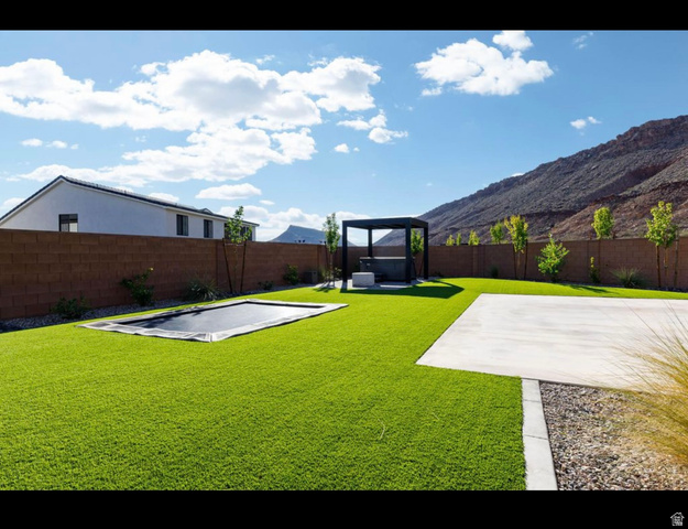 2788 East Rill Drive Washington, UT 84780 - Photo 40 of 41 Expansive artificial turf backyard featuring a built-in ground trampoline, a concrete patio area, and a dark-framed pergola structure