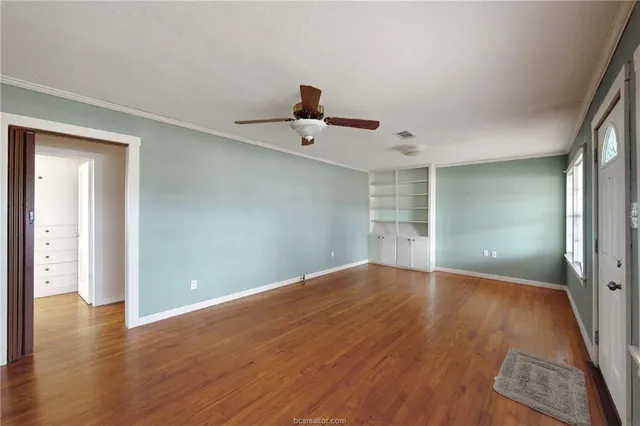 a view of a room with wooden floor and a ceiling fan