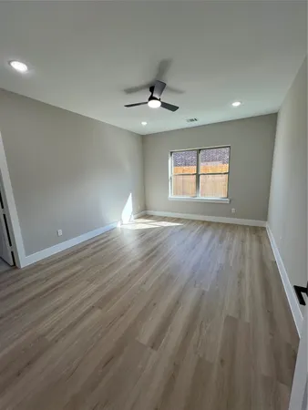 an empty room with wooden floor chandelier fan and windows