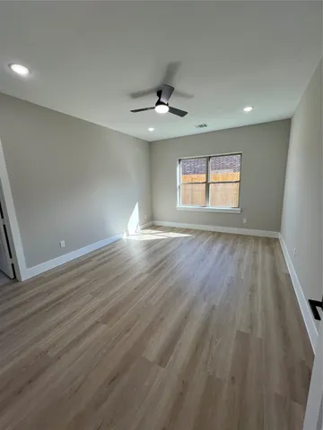 an empty room with wooden floor chandelier fan and windows