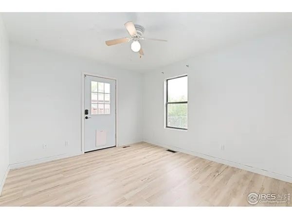 a view of an empty room with wooden floor and a window
