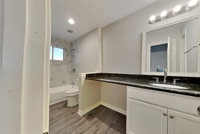 a bathroom with a granite countertop sink a toilet and a mirror