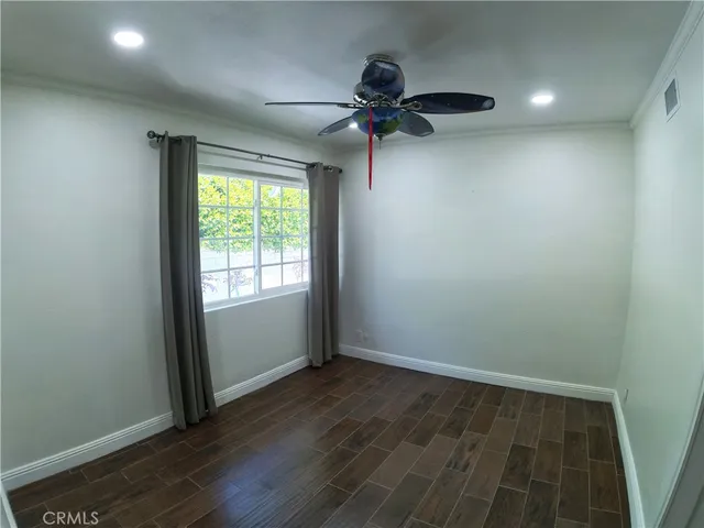 an empty room with wooden floor fan and windows
