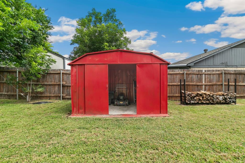 909 North Dove Road Grapevine, TX 76051 - Photo 29 of 30 Spacious backyard featuring a red metal storage shed and a wood fence perimeter