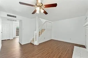 an empty room with wooden floor fan and windows