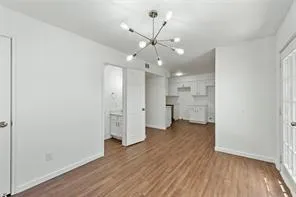 an empty room with wooden floor and a hallway