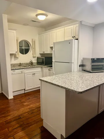 a kitchen with granite countertop a sink and a refrigerator