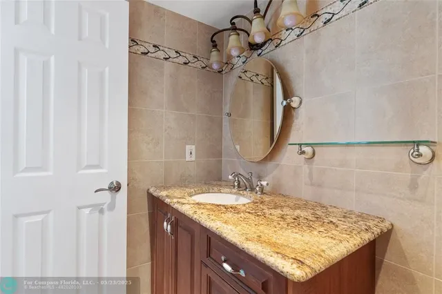 a bathroom with a granite countertop sink a mirror and shower