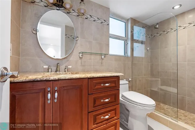 a bathroom with a granite countertop toilet sink shower and mirror
