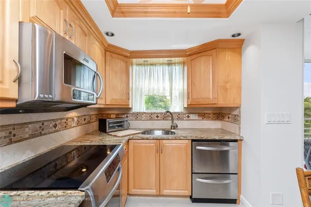 a kitchen with granite countertop a sink a stove and cabinets