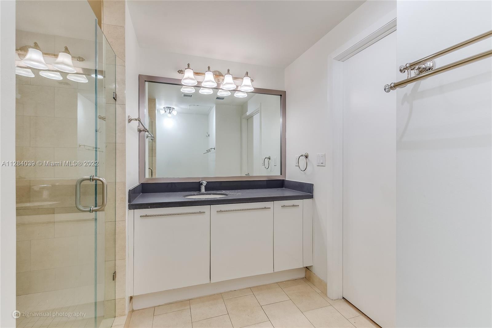 90 Southwest 3rd Street, Unit 3012 Miami, FL 33130 - Photo 10 of 16 a bathroom with a granite countertop sink a mirror and a shower