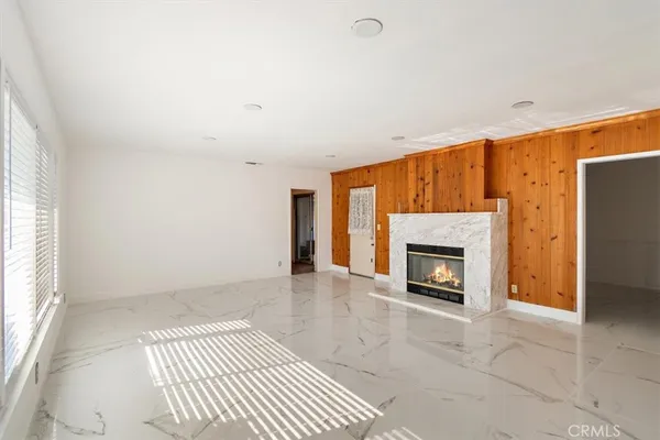 a living room with a fireplace furniture a ceiling fan and a window