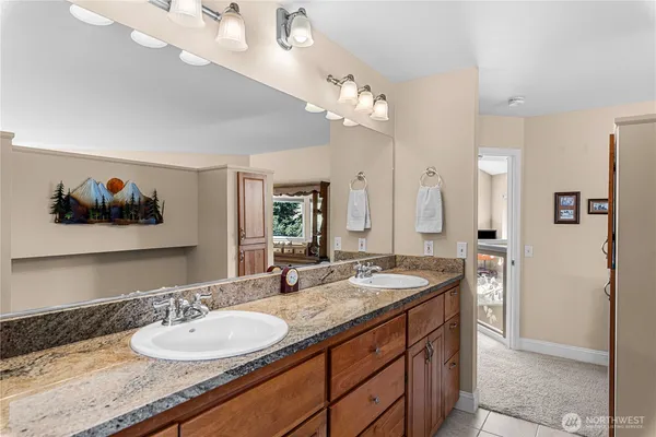 a bathroom with a granite countertop double vanity sink and a mirror