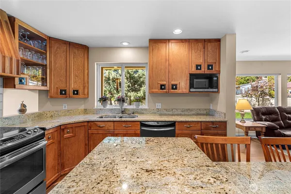 a large kitchen with stainless steel appliances granite countertop a stove sink and cabinets