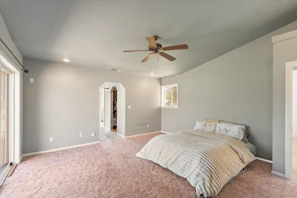 a bedroom with a bed ceiling fan and a window