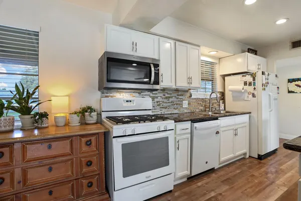 a kitchen with cabinets stainless steel appliances a sink and wooden floor