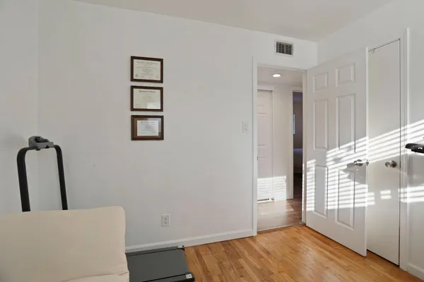 a view of empty room with wooden floor and fan