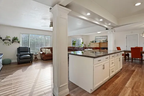 a kitchen with sink refrigerator and couches with wooden floor