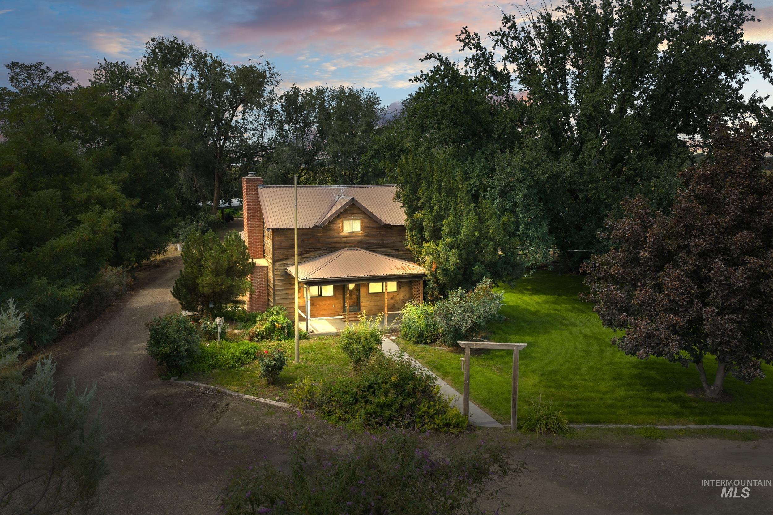 31637 Apple Valley Road Parma, ID 83660 - Photo 1 of 1 View of front of home featuring a lawn, a porch, a chimney, dirt driveway, and a metal roof