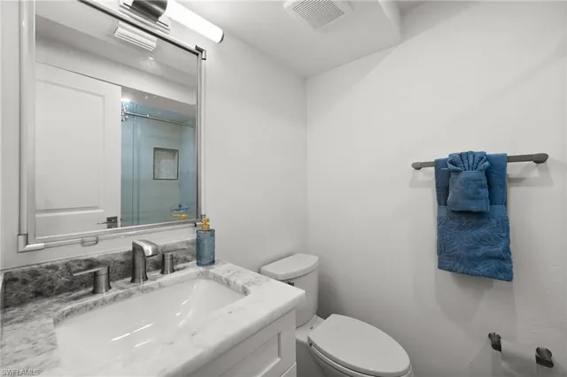a bathroom with a granite countertop toilet sink and mirror