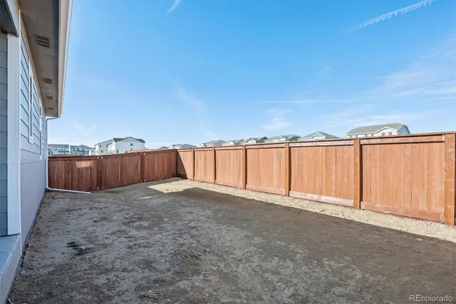 a view of an empty room with wooden floor and fence