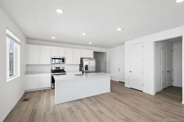 a kitchen with stainless steel appliances a stove top oven a sink with wooden floors and cabinets