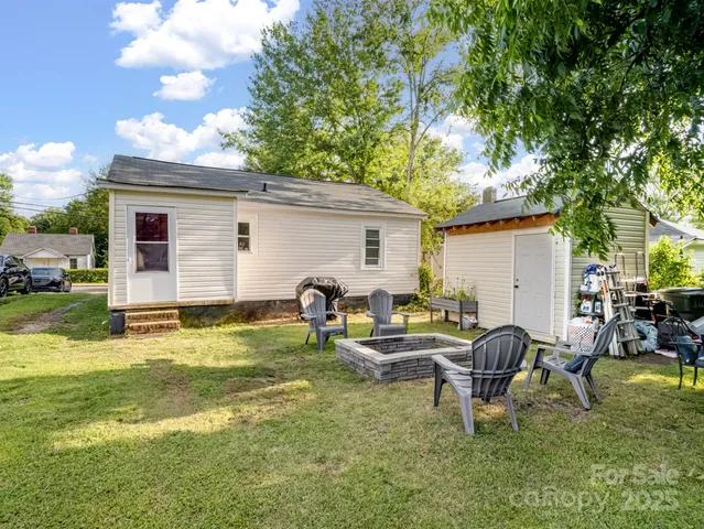 a view of backyard of house with outdoor seating and trees in the background
