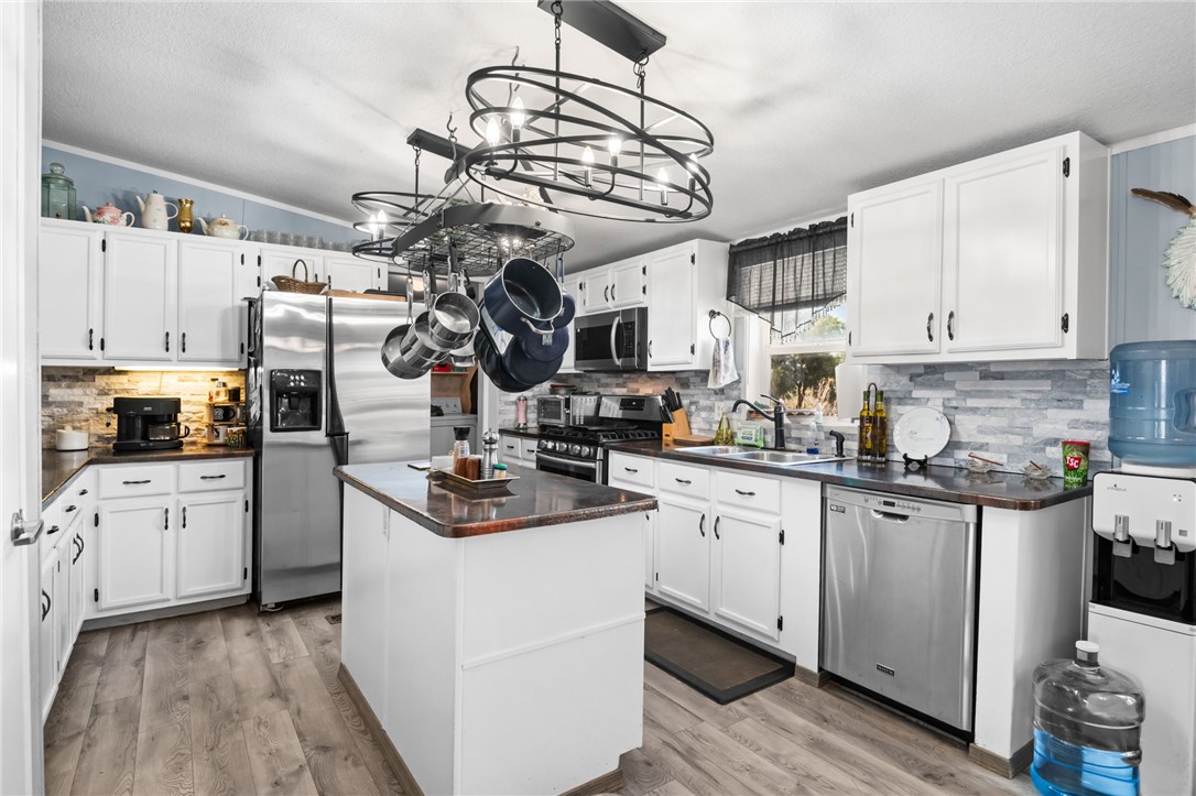 3411 Mayer Road Golden Valley, AZ 86413 - Photo 6 of 49 Kitchen featuring stainless steel appliances, a center island, white cabinets, decorative light fixtures, and light wood-style floors