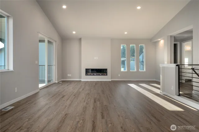 an empty room with wooden floor windows and fireplace
