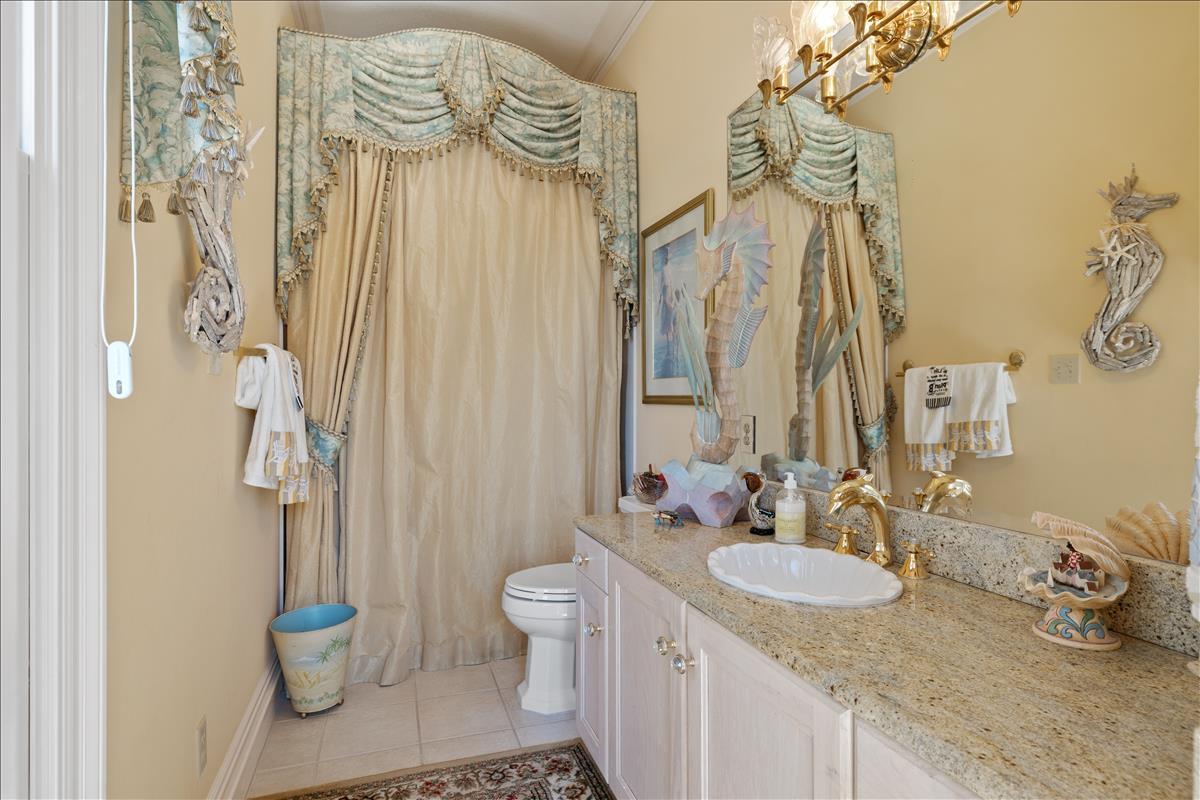 83 Poquito Road Shalimar, FL 32579 - Photo 33 of 83 a bathroom with a granite countertop sink a toilet and a shower curtain