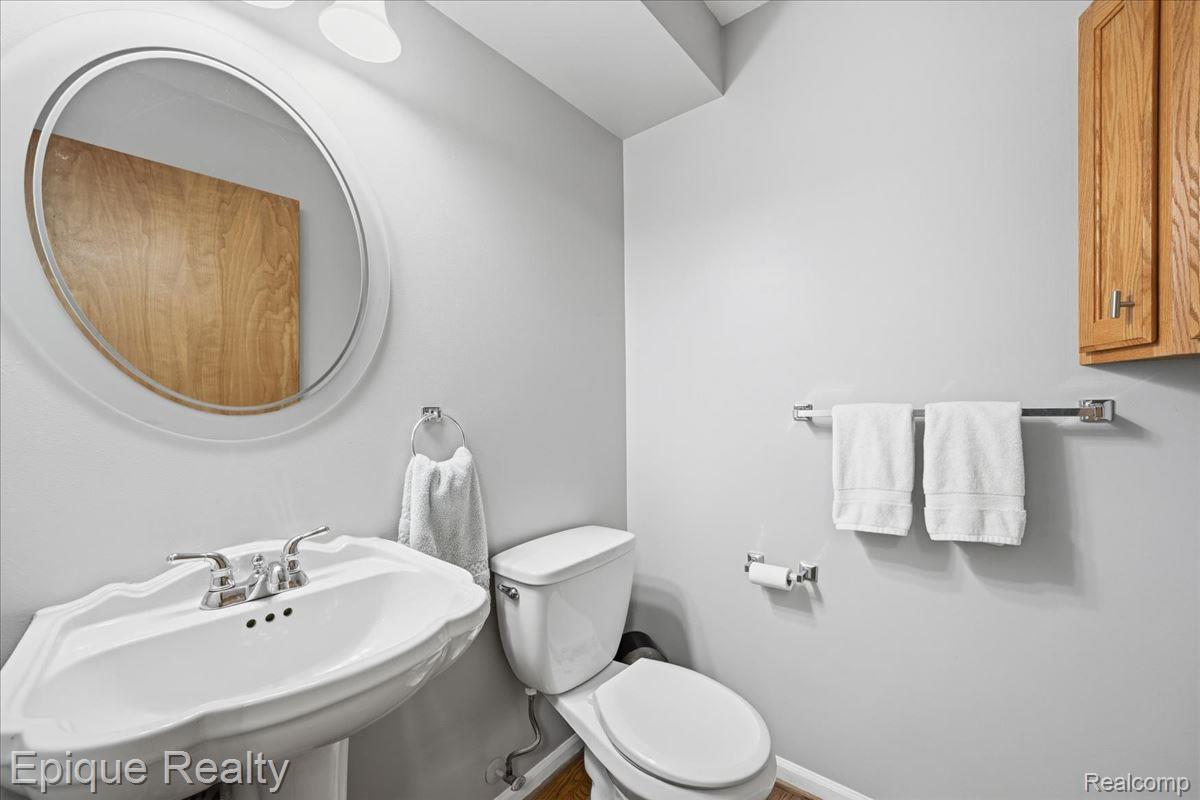 1221 Rhodes Road Lake Orion, MI 48360 - Photo 24 of 72 Pedestal sink with chrome fixtures and a round wall-mounted mirror