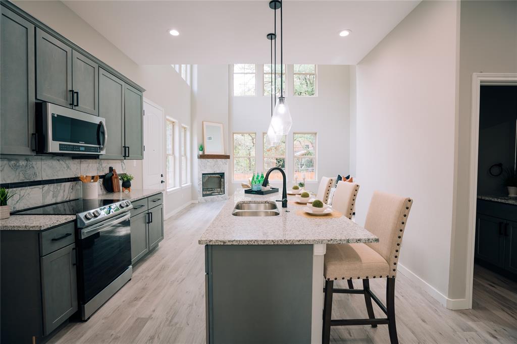 a large kitchen with stainless steel appliances kitchen island granite countertop a stove a sink a refrigerator and a dining table with wooden floor
