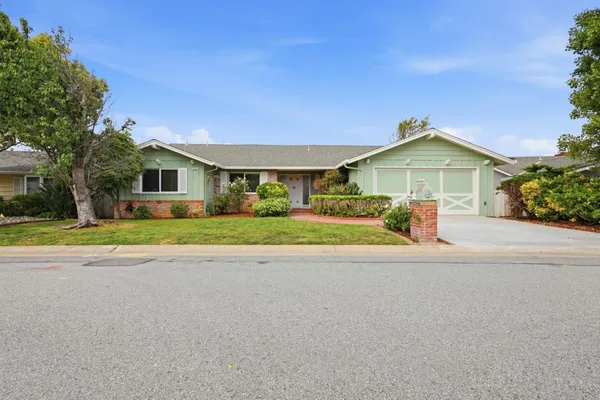 a front view of a house with a yard and potted plants