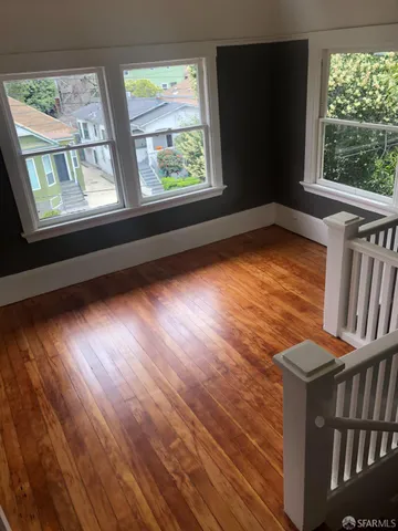 a view of kitchen and empty room with wooden floor