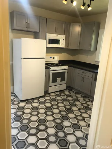 a kitchen with granite countertop a refrigerator a stove top oven and a sink