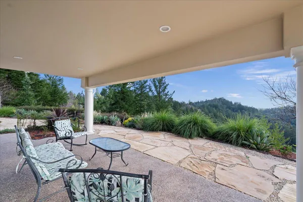 an aerial view of a house with outdoor space and trees all around