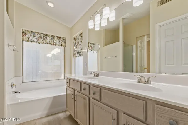 a bathroom with a double vanity sink mirror and a bathtub